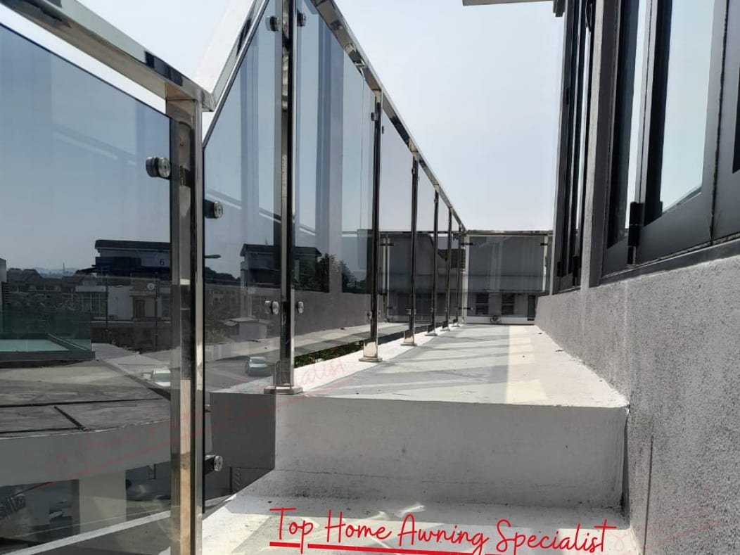 A covered walkway with a glass roof and a glass balustrade running alongside a flight of entrance steps up to a house.