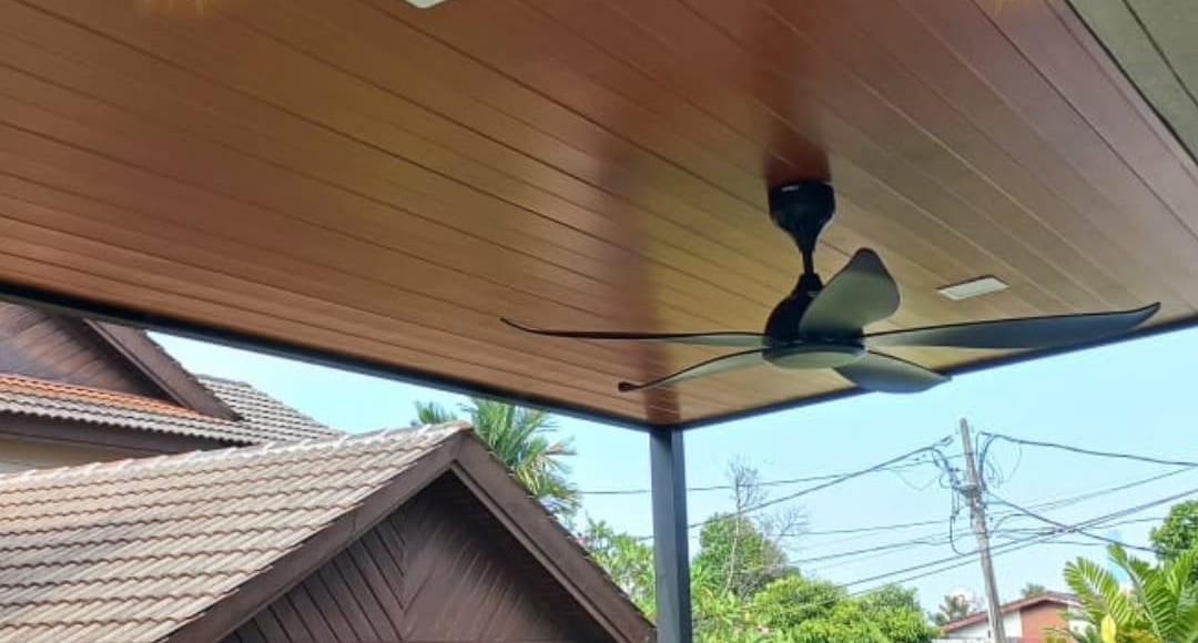 Close up of a wood-grain aluminium soffit with a recessed light panel set into it and a black ceiling fan mounted below.
