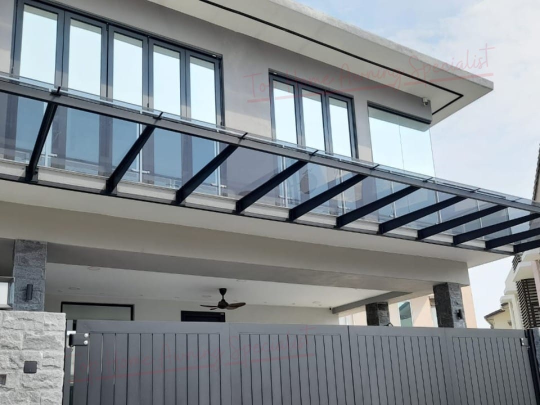 The front of a modern two-storey house with a glass roof on a black steel frame running the full width of the car porch and continuing past a dark slatted gate.