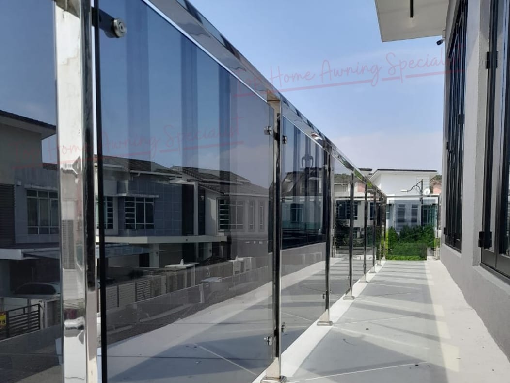 A glass roof over the narrow side path between two houses, carried on slim posts with a glass balustrade alongside.